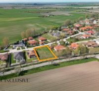 Na predaj 1046 m² stavebný pozemok, Malé Dvorníky - Pozemky - bývanie v Malých Dvorníkoch, zasadené medzi úhľadné rodinné domy a zelené polia.