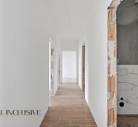 Na predaj 4-izbové novostavby, Veľká Paka - Chodba v rodinnom dome s bielymi stenami a podlahou s dreveným dekorom.