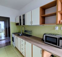 2izbový byt na prenájom v Dubnici nad Váhom  - Kuchyňa v 2-izbovom byte s mikrovlnkou a varnou doskou, smerujúca do ďalšej miestnosti.
