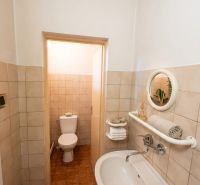 Vidiecky dom na predaj Mikulášov - Kúpeľňa v rodinnom dome s umývadlom, zrkadlom a toaletou, dlažba s hnedým dekorom.