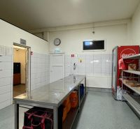 ODSTÚPENIE gastro prevádzky PIZZA Top v Nitre - Gastro priestory so skladom, bielymi obkladmi, chladničkou a kovovými regálmi na uskladnenie.