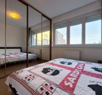 | priestranný | 2i byt s balkónom | parkovaním | Koprivnická - Spálňa s veľkou zrkadlovou skriňou v 2-izbovom byte, podlaha s dreveným dekorom.