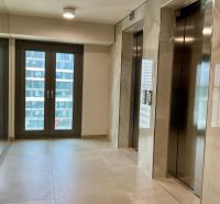 I Predaj Výnimočný  1-izb apartmán v projekte Metropolis - Výťahová hala v budove Bratislava - Staré Mesto so sklenými dverami a svetlými obkladačkami.