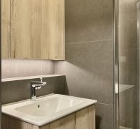 I Predaj Výnimočný  1-izb apartmán v projekte Metropolis - Kúpeľňa so svetlým dreveným nábytkom a tmavými obkladmi v 1-izbovom byte.