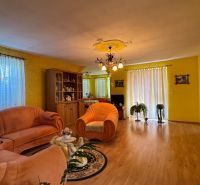 NA PREDAJ 4 izbový rodinný dom Nitrianske Hrnčiarovce - Obývacia izba v rodinnom dome s oranžovými sedačkami a podlahou s dreveným dekorom.