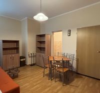 NA PREDAJ Ubytovňa v obci Bílkové Humence - Obývacia izba s oranžovým gaučom, jedálenským stolom a skriňami, pripomínajúca hotely a penzióny.