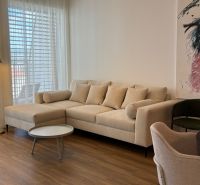 NA PRENÁJOM 2 izbový byt priamo v centre Nitry  - Svetlá obývacia izba s krémovou sedačkou, umením na stene a podlahou s dreveným dekorom.
