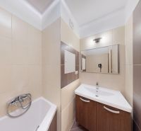 Priestranný a zariadený 3-izbový byt s lodžiou, Drobného - Kúpeľňa v 3-izbovom byte so sprchou, umývadlom a obkladmi v hnedých odtieňoch.
