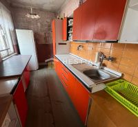 NOVINKA NA TRHU | Rodinný dom v obci Cerová – ideálne miesto pre pokoj - Kuchyňa v rodinnom dome s oranžovými skrinkami a podlahou s dreveným dekorom.