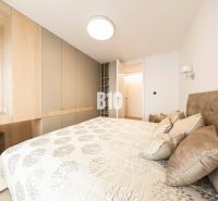 POD VINICAMI - 3IZBOVÉ BYTY V NADŠTANDARDNEJ BOUTIQUE REZIDENCII - Spálňa v 3-izbovom byte s úložnými priestormi a posteľou so vzorovanými textíliami.