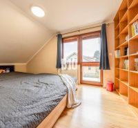 6-IZBOVÝ DOM S DVOJGARÁŽOU A VEĽKORYSÝM PRIESTOROM PRE CELÚ RODINU V P - Podkrovná izba s posteľou, knihovnicou a podlahou s dreveným dekorom v rodinnom dome.