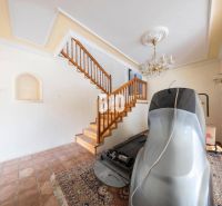 NADČASOVÝ 5-IZBOVÝ RODINNÝ DOM PRI HRÁDZI – HAMULIAKOVO - Interiér rodinného domu so schodiskom, lustrom, podlahou a športovým zariadením.