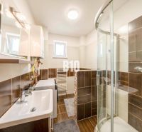 ŠTARTOVACÍ 2-IZBOVÝ BYT S KLIMATIZÁCIOU,  BALKÓNOM, PARKOVACÍM STÁTÍM  - Kúpeľňa v 2-izbovom byte s tmavými obkladmi a sprchovacím kútom.