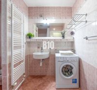 Praktický 2-izbový byt so samostatnou kuchyňou, Kvetná ulica – Nivy - Kúpeľňa s práčkou, umývadlom a toaletou v 2-izbovom byte. Svieže rastliny dodávajú šarm.