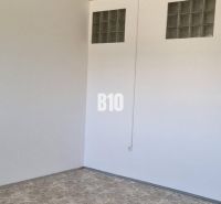 Prenájom obchodných a kancelárskych priestorov - Biela stena so sklenými tvárnicami, podlaha s dreveným dekorom, obchodné priestory.