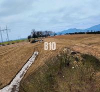 Veľký stavebný pozemok na predaj - Laskár - Kopcovitá krajina v Laskári vhodná pre pozemky na bývanie, s elektrickým vedením v pozadí.