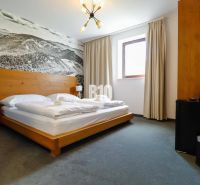 VKUSNE ZARIADENÝ apartmán v TOP lokalite v lyž. stredisku SNOWLAND Val - Spálňa v rekreačnom apartmáne s drevenou posteľou a veľkoformátovou fotografiou krajiny.