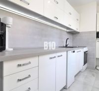 REZERVOVANÉ Štýlový 2-izbový byt s privátnym dvorom v srdci Podhája - Kuchyňa v 2-izbovom byte s bielymi spotrebičmi a sivými prvkami.