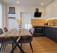 KRÁĽOVSKÝCH 82 m²: Kompletne zrekonštruovaný 3-izbový byt v centre Mar - Kuchyňa v 3-izbovom byte s dreveným dekorom, stolom a farebnými stoličkami.