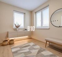 Rodinný dom s rovinatým 10a pozemkom - Interiér rodinného domu s lavicou, okrúhlym zrkadlom a podlahou s dreveným dekorom.