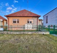Rodinný dom s rovinatým 10a pozemkom - Rodinný dom v Sľažanoch s predzáhradkou a šikmou strechou medzi susednými budovami.