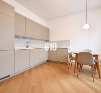 Rodinný dom s rovinatým 10a pozemkom - Kuchyňa v rodinnom dome s podlahou s dreveným dekorom a jedálenským stolom so stoličkami.