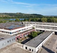 Veľkometrážne VÝROBNÉ HALY v priemyselnej zóne Géňa - Levice - Výrobné priestory v Leviciach s opustenými budovami obklopené prírodou a vodnou plochou.