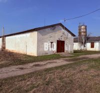 Výhodný hospodársky areál v obci Turá - Výrobné priestory v Turej s poľnohospodárskou architektúrou a silom na pozadí.