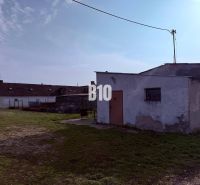 Výhodný hospodársky areál v obci Turá - Výrobné priestory v exteriéri v meste Turá s jednoduchými stavbami a trávnatou plochou.