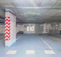 Výnimočný byt s panoramatickým výhľadom na Zobor - Podzemné parkovisko v Nitre s označeným parkovacím miestom a betónovými stĺpmi.