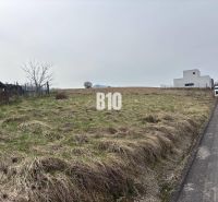 PRESTÍŽNY STAVEBNÝ POZEMOK S PROJEKTOM – ROSINA PRI ŽILINE - Pozemok na bývanie v Rosine, vedľa cesty, s trávnatým povrchom a neďalekými stavbami.