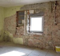 Rodinný dom na rekonštrukciu, 660m2 pozemok. - Izba v rodinnom dome s tehlovými stenami a vedrom na podlahe.
