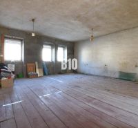 Rodinný dom na rekonštrukciu, 660m2 pozemok. - Priestranná miestnosť v Rodinnom dome s drevenou podlahou a nedokončenými stenami.