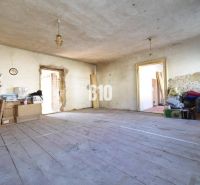 Rodinný dom na rekonštrukciu, 660m2 pozemok. - Neporiadna miestnosť v rodinnom dome s drevenou podlahou a stavebným materiálom.