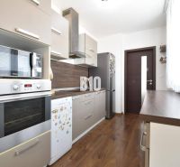 3-izbový byt s parkovaním vo dvore - Kuchyňa v 3-izbovom byte s podlahou s dreveným dekorom a modernými spotrebičmi.