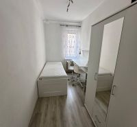 Prenájom moderný 2,5 izbový byt, Šalviová ulica, Bratislava II.Ružinov - Jednoduchá izba s posteľou, skriňou a stolom, podlaha s dreveným dekorom.