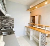 Štartovací byt s balkónom a výhľadom, ktorý vás bude baviť! - Kuchyňa v 1-izbovom byte s barovým pultom a podlahou s dreveným dekorom.