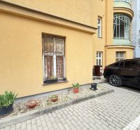 VEĽKORYSÝ 2i byt s rozlohou 76 m² v atraktívnej lokalite- Staré mesto - Parkovanie pred budovou na Leškovej v Bratislave s kvetináčmi a zaparkovaným autom.