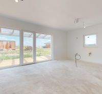 NOVY SVET - SKOLAUDOVANÝ rodinný dom s terasou a parkovaním - Priestranná izba s veľkými oknami a betónovou podlahou v rodinnom dome.