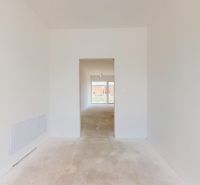 NOVY SVET - SKOLAUDOVANÝ rodinný dom s terasou a parkovaním - Prázdna miestnosť v rodinnom dome s bielymi stenami a betónovou podlahou.