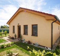 4-izbová novostavba rodinného domu s terasou, Andovce - Rodinný dom v Andovciach s upravenou záhradou, žltou fasádou a šikmou strechou.