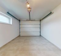 DUNAJSKÁ STREDA- 4i moderná novostavba RD s tep. čerpadlom + garážou - Garáž v rodinnom dome s veľkou vstupnou bránou a oknom na bočnej stene.