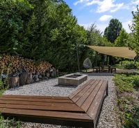 Na predaj nádherný 4 izbový luxusný byt,176 m2 + terasy 55 m2,2 garáž. - Záhrada s drevenou lavicou, krbom a tieniacou plachtou pri 4-izbovom byte na Rekreačnej v Piešťanoch.
