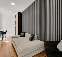Na predaj nádherný 4 izbový luxusný byt,176 m2 + terasy 55 m2,2 garáž. - Moderný interiér s pohovkou, kreslom, pracovným stolom a vertikálnou stenou v 4-izbovom byte.