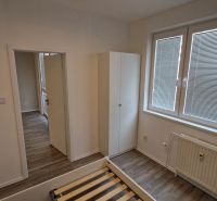 Predaj útulný, úplne prerobený 2 izbový byt s loggiou, Rajecká ulica. - Spálňa v 2-izbovom byte s bielymi stenami a podlahou s dreveným dekorom.