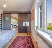 Prenájom | 2-izbový byt | Záhradnícka – Poľská ulica | 900 € + 200 € e - Spálňa v 2-izbovom byte s kobercom a podlahou s dreveným dekorom.