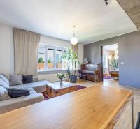 Prenájom | 2-izbový byt | Záhradnícka – Poľská ulica | 900 € + 200 € e - Obývacia izba v 2-izbovom byte s pohovkou, klavírom a podlahou s dreveným dekorom.