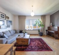 Prenájom | 2-izbový byt | Záhradnícka – Poľská ulica | 900 € + 200 € e - Obývačka s rohovou sedačkou, kobercom, klavírom a podlahou s dreveným dekorom.