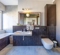 Prenájom | 2-izbový byt | Záhradnícka – Poľská ulica | 900 € + 200 € e - Kúpeľňa v 2-izbovom byte s vaňou, umývadlom, zrkadlom, výhľadom z okna a tmavými obkladmi.