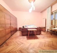 Priestranný pôvodný dom na rozľahlom pozemku v centre obce Gbelce - Spálňa v rodinnom dome s podlahou s dreveným dekorom, luster, skrine, stoličky.
